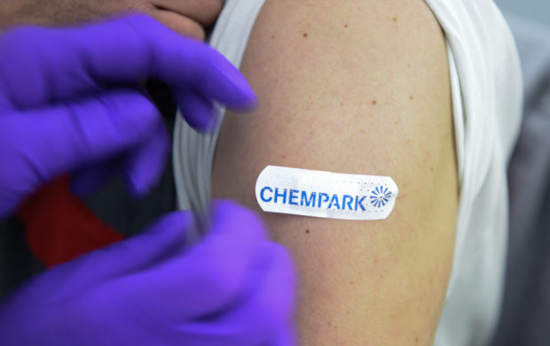 A doctor fixes a patch on the arm of an employee after a vaccination with the Pfizer BioNTech vaccine at the vaccination center of CHEMPARK operator CURRENTA in Leverkusen, western Germany, on June 22, 2021, amid the ongoing coronavirus (Covid-19) pandemic. - Since June the prioritisation for vaccination against Covid-19 has been lifted nationwide. Now the company doctors at the sites in the CHEMPARKS of Leverkusen, Krefeld-Uerdingen and Dormagen can vaccinate the approx. 35000 employees. It is a joint initiative of the companies located at the CHEMPARK sites, which include CHEMPARK operator CURRENTA, LANXESS, Bayer and Covestro. (Photo by Ina FASSBENDER / AFP)