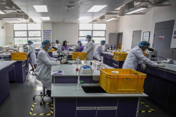 Medical technology students work in a laboratory as limited face-to-face classes resume at the University of Santo Tomas in Manila on October 20, 2021, ahead of a government plan to pilot face-to-face primary and secondary classes on November 15 in COVID-19 low risk areas. (Photo by JAM STA ROSA / AFP)