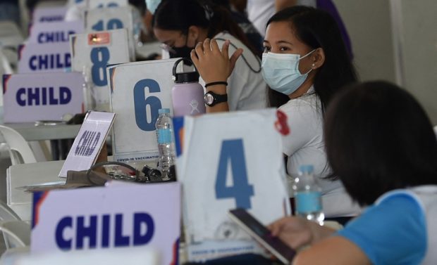 Health workers wait to interview children during a vaccination drive against Covid-19 at a sports complex in Marikina, suburban Manila on October 22, 2021, after the national government expanded its innoculation program against Covid-19 to children with comorbidities aged 12-17. (Photo by Ted ALJIBE / AFP)