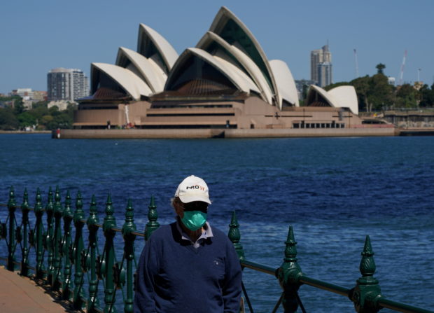 A person in protective face mask walks along the harbour waterfront across from the Sydney Opera House during a lockdown to curb the spread of coronavirus disease (COVID-19) outbreak in Sydney, Australia, October 6, 2021. REUTERS/Loren Elliott