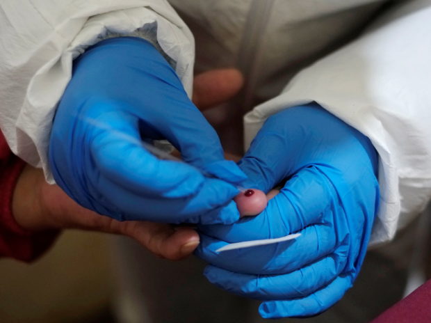 FILE PHOTO: A medical worker takes a blood sample from a saleswoman during a voluntary rapid antigen testing campaign for the coronavirus disease (COVID-19) at the Sopocachi market in La Paz, Bolivia, December 26, 2020. REUTERS/David Mercado; blood clot