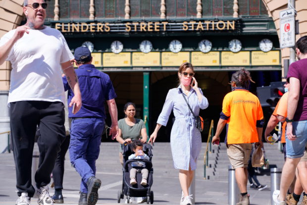 Pedestrians walk in front of Flinders Street Station on the first day of eased coronavirus disease (COVID-19) regulations, following a lockdown to curb an outbreak, in Melbourne, Australia, October 22, 2021. REUTERS/Sandra Sanders
