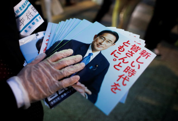 An election campaign staff member holds leaflets of Japan's ruling Liberal Democratic Party with cover photos of Japan's Prime Minister and the party's president Fumio Kishida, as he distributes these to voters during an election campaign on the first day of campaigning for the upcoming lower house election, amid the coronavirus disease (COVID-19) pandemic, in Tokyo, Japan October 19, 2021.  REUTERS/Issei Kato