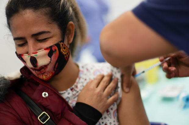 A woman receives a dose of Pfizer/BioNTech coronavirus disease (COVID-19) vaccine during a vaccination campaign inside the University of Santiago, Chile June 30, 2021. REUTERS/Ivan Alvarado