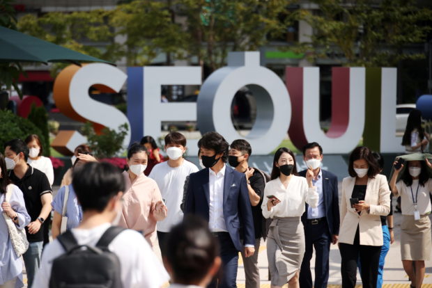 Commuters wearing masks to avoid contracting the coronavirus disease (COVID-19) walk on a zebra crossing in Seoul, South Korea, September 24, 2021. REUTERS/Kim Hong-Ji