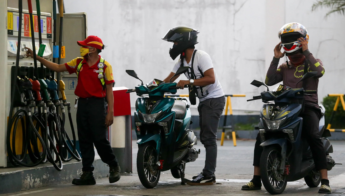 FILE PHOTO: A gasoline station attendant in Quezon City assists motorcycle riders on Monday as vehicle owners start queueing to fill their tanks ahead of another fuel price increase. —LYN RILLON