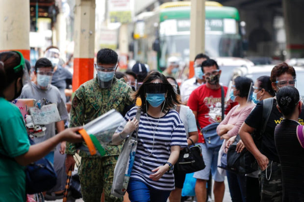 FILE PHOTO: People wear face mask and face shields to help curb the spread of COVID-19 as they walk along the streets in Quezon city, Philippines on Wednesday, Aug. 19, 2020. Philippine President Rodrigo Duterte has decided to ease a mild coronavirus lockdown in the capital and four outlying provinces to further reopen the country's battered economy despite having the most reported infections in Southeast Asia. (AP Photo/Aaron Favila) alert level ncr