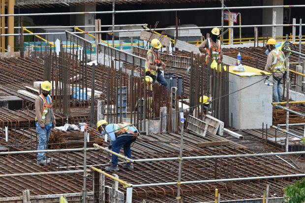 In this photograph taken on September 14, 2021 migrant workers are pictured working at a construction site in Singapore. - More than 300,000 migrant workers live in packed dorms in Singapore, and the vast complexes that were hit hard by Covid-19 and locked down at the start of the pandemic remain subject to strict restrictions 18 months later. (Photo by ROSLAN RAHMAN / AFP) / To go with 'SINGAPORE-HEALTH-VIRUS-MIGRATION-LABOUR,FOCUS' by Catherine LAI