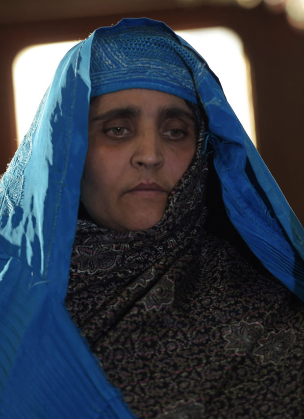 Afghan refugee Sharbat Gula, 45, looks on as she meets with Afghan President Ashraf Ghani at the Presidential Palace in Kabul on November 9, 2016. - An Afghan woman immortalised on a National Geographic cover was deported by Pakistani officials early November 9 to her war-torn homeland following a brief period of detention for using fraudulent identity papers. Sharbat Gula, whose blazing green eyes were captured in an image taken in a Pakistan refugee camp in the 1980s that became the magazine's most famous cover, was discharged from hospital where she was being treated for Hepatitis C and taken to the border overnight, officials said. (Photo by SHAH MARAI / AFP)
