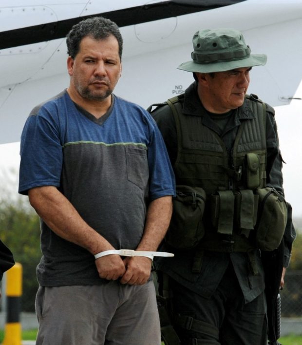 Daniel Rendon Herrera (C), a.k.a. "Don Mario", is heavily escorted by police officers on April 15, 2009 in Bogota, Colombia. Rendon Herrera, Colombia's biggest drug kingpin for whom the government had offered a 2.1-million-dollar bounty, was arrested by a special unit of 315 police in Antioquia Department. AFP PHOTO/Rodrigo Arangua (Photo by RODRIGO ARANGUA / AFP)