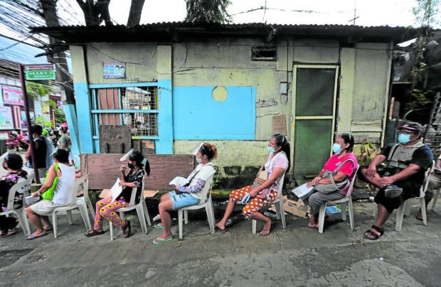 WAITING FOR AID In this photo taken in August, residents of Payatas village in Quezon City queue to receive cash aid from the government. A proposal to delay the release of the subsidy for unvaccinated beneficiaries of the conditional cash transfer program is being discussed by government agencies. —GRIG C. MONTEGRANDE