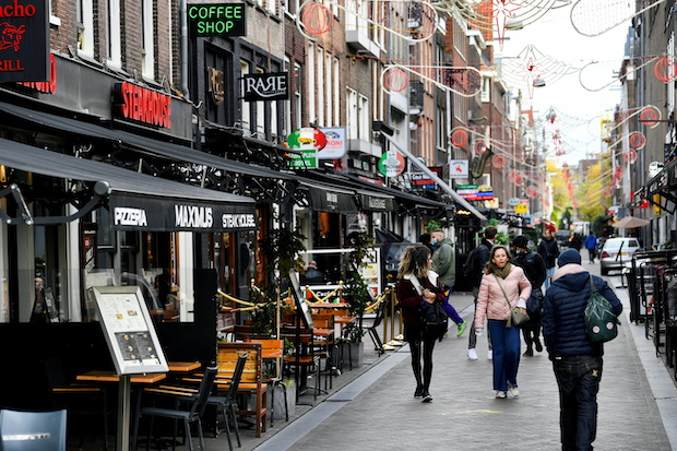 People walk past restaurants and bars in Amsterdam