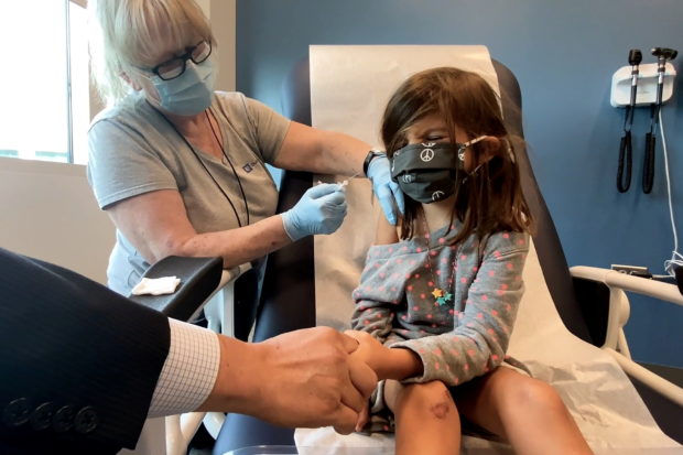 FILE PHOTO: Bridgette Melo, 5, reacts as she holds the hand of her father, Jim Melo, during her inoculation of one of two reduced 10 ug doses of the Pfizer BioNtech COVID-19 vaccine during a trial at Duke University in Durham, North Carolina September 28, 2021 in a still image from video. Video taken September 28, 2021. Shawn Rocco/Duke University/Handout via REUTERS