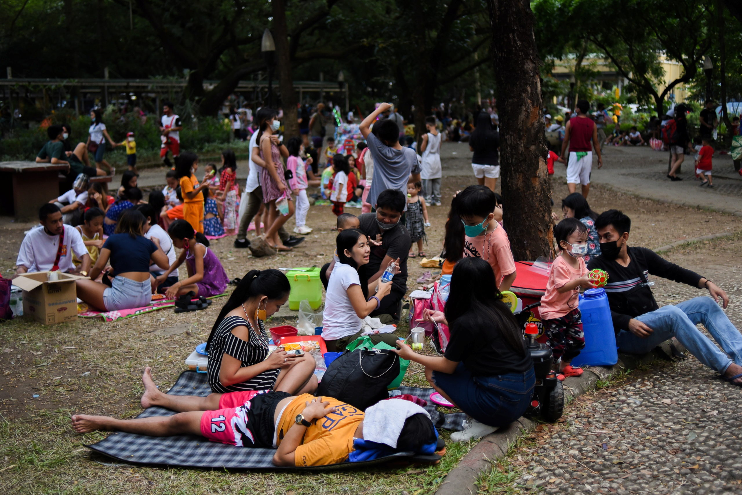 Parents and children relax at a public park, as the country's capital region loosens coronavirus disease (COVID-19) restrictions, in Quezon City, Metro Manila, Philippines, November 2, 2021. Picture taken November 2, 2021. REUTERS/Lisa Marie David