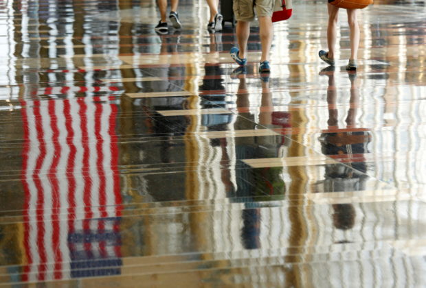 FILE PHOTO: A U.S. flag is reflected on the floor as passengers make their way through Reagan National Airport in Washington, U.S., July 1, 2016. REUTERS/Kevin Lamarque/File Photo/File Photo