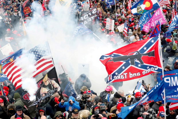 FILE PHOTO: Tear gas is released into a crowd of protesters, with one wielding a Confederate battle flag that reads "Come and Take It," during clashes with Capitol police at a rally to contest the certification of the 2020 U.S. presidential election results by the U.S. Congress, at the U.S. Capitol Building in Washington, U.S, January 6, 2021. REUTERS/Shannon Stapleton