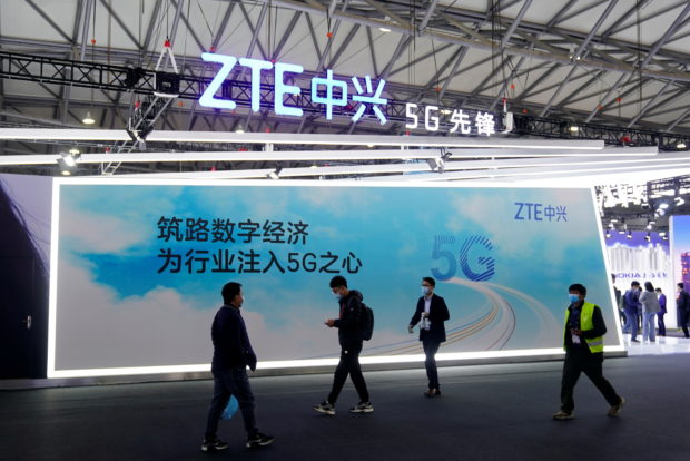 FILE PHOTO: People walk past a ZTE Corp booth at the Mobile World Congress (MWC) in Shanghai, China February 23, 2021. REUTERS/Aly Song