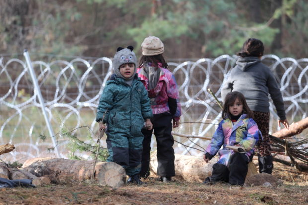 FILE PHOTO: Children gather near a barbed wire fence in a migrants' makeshift camp on the Belarusian-Polish border in the Grodno region, Belarus November 12, 2021. Ramil Nasibulin/BelTA/Handout via REUTERS