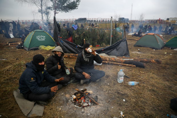 Migrants gather around a fire in a camp near Bruzgi-Kuznica checkpoint on the Belarusian-Polish border in the Grodno region, Belarus, November 18, 2021.  REUTERS/Kacper Pempel