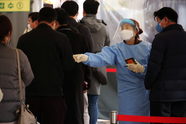 FILE PHOTO: A health worker directs people arriving to undergo coronavirus disease (COVID-19) tests, at a testing site in Seoul, South Korea, November 10, 2021. REUTERS/Kim Hong-Ji