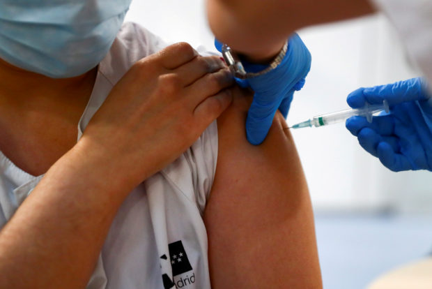 FILE PHOTO: A health worker receives a dose of the Pfizer-BioNTech COVID-19 vaccine in Madrid, Spain, February 4, 2021. REUTERS/Sergio Perez