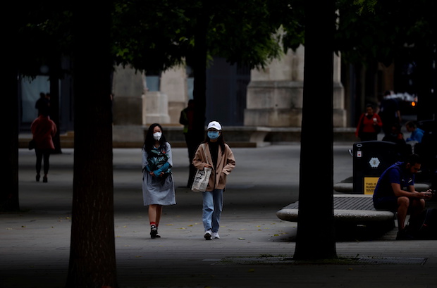 People wear protective masks as they walk through the city centre, amid the outbreak of the coronavirus disease (COVID-19) in Manchester