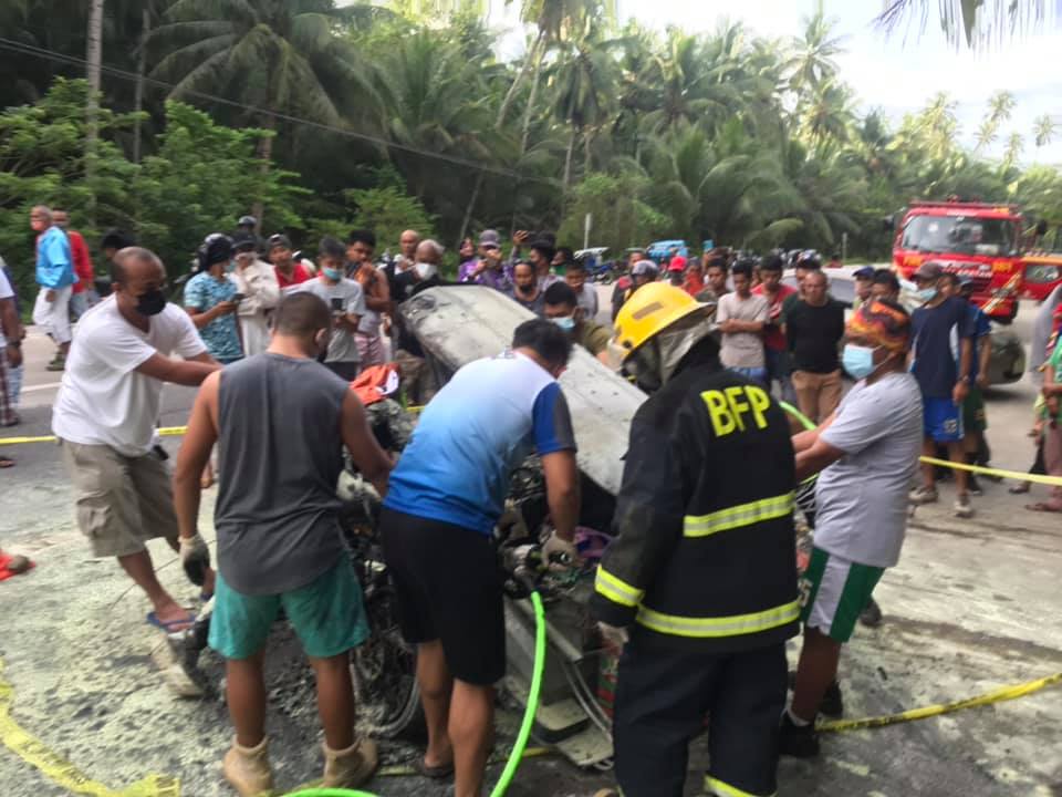 Disaster responders try to remove the charred remains of a tricycle driver whose vehicle went on fire after colliding with a motorcycle in Malapatan town, Sarangani province