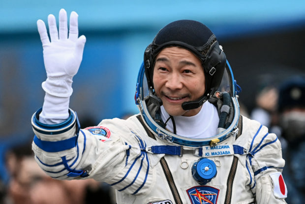 Japanese billionaire Yusaku Maezawa waves before boarding the Soyuz MS-20 spacecraft prior to the launch at the Baikonur cosmodrome on December 8, 2021. - Japanese billionaire Yusaku Maezawa and his assistant Yozo Hirano, led by Roscosmos cosmonaut Alexander Misurkin, will blast off to the International Space Station (ISS) onboard the Soyuz MS-20 spacecraft from the Russia-leased Baikonur cosmodrome in Kazakhstan at 0738 GMT. (Photo by Kirill KUDRYAVTSEV / POOL / AFP)