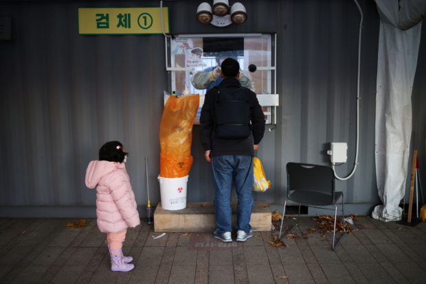 A girl waits for his father undergoing coronavirus disease (COVID-19) test at its testing site in central Seoul, South Korea, December 1, 2021.    REUTERS/Kim Hong-Ji
