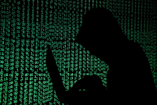 FILE PHOTO: A hooded man holds a laptop computer as cyber code is projected on him in this illustration picture taken on May 13, 2017. REUTERS/Kacper Pempel/Illustration/File Photo