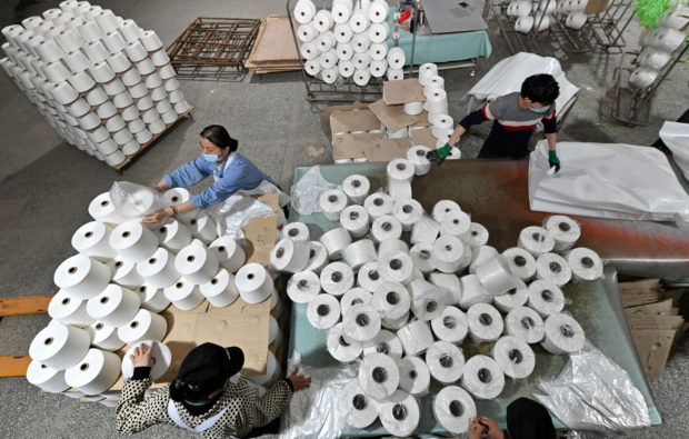 FILE PHOTO: Workers are seen on the production line at a cotton textile factory in Korla, Xinjiang Uighur Autonomous Region, China April 1, 2021. Picture taken April 1, 2021. cnsphoto via REUTERS /File Photo