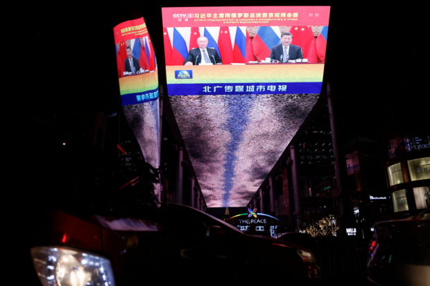 A giant screen broadcasts news footage of a virtual meeting between Chinese President Xi Jinping and Russian President Vladimir Putin, at a shopping mall in Beijing, China, December 15, 2021. REUTERS/Carlos Garcia Rawlins