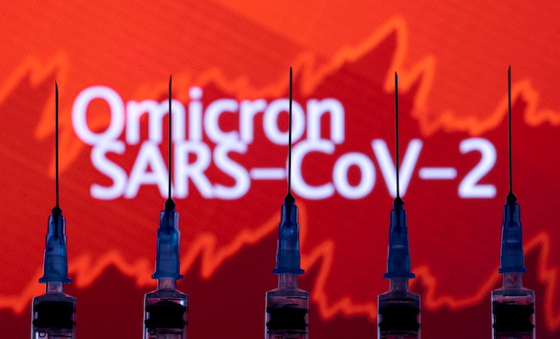 \Syringes with needles are seen in front of a displayed stock graph and words "Omicron SARS-CoV-2" in this illustration taken