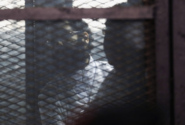 Activist Alaa Abdel Fattah stands behind bars before his verdict is announced at a court in Cairo, February 23, 2015. REUTERS/Asmaa Waguih/Files
