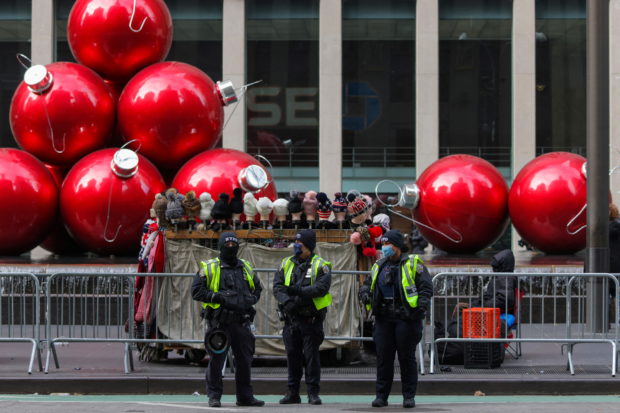 FILE PHOTO: Members of the New York City Police Department (NYPD) wear face masks as they stand in front of holiday decorations on Sixth Avenue as the Omicron coronavirus variant continues to spread in Manhattan, New York City, U.S., December 19, 2021. REUTERS/Andrew Kelly
