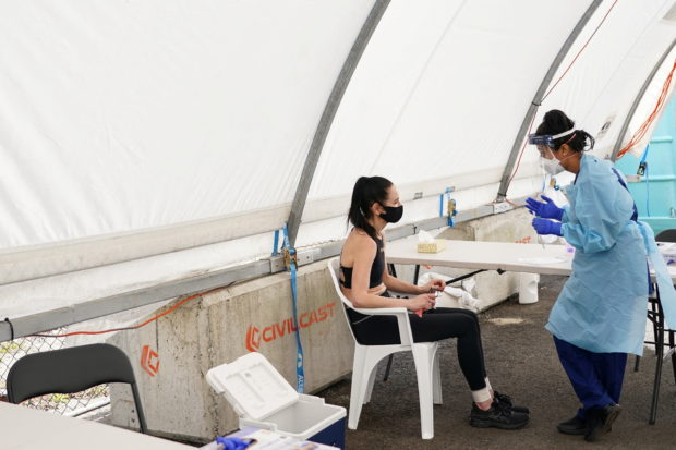 FILE PHOTO: A medical worker prepares to administer a test for the coronavirus disease (COVID-19) on a member of the public at a pop-up testing centre in Sydney, Australia, August 30, 2021. REUTERS/Loren Elliott