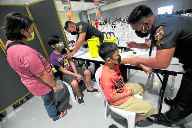 GOOD BOYS Two young men get their first jabs at SM Megamall during the National Vaccination Day on Nov. 29. —NIñO JESUS ORBETA