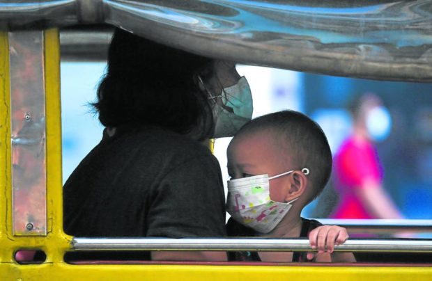 SAFE COMMUTE A mother ensures that she and her child are masked as they take a jeepney in Marikina City. While COVID-19 cases are dropping in Metro Manila, health officials still urge the public to continue observing health protocols to stop another infection surge. —LYN RILLON
