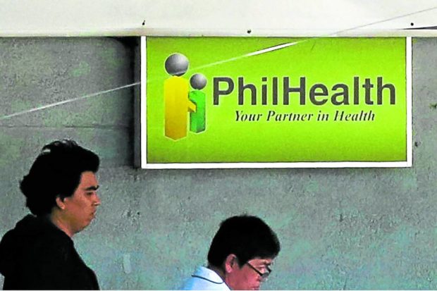 People in front of a PhilHealth sign. STORY: Filipinos shoulder up to 44.7% of hospital fees even with PhilHealth