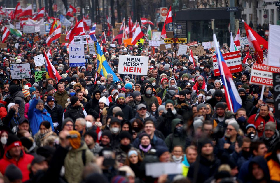 Demonstrators hold flags and placards as they march to protest against the coronavirus disease (COVID-19) restrictions and the vaccine mandate in Vienna, Austria