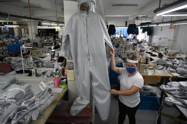Marlene Cenina, 39, sewer, poses for a picture inside the factory where she works making Personal Protective Equipment (PPE) for frontliners during the COVID-19 coronavirus pandemic, in Cainta, Philippines, on April 24, 2020. - Ahead of May Day on May 1, 2020, AFP portrayed workers defying the novel coronavirus around the world. Marlene Cenina lost her job as a sewer after the lockdown and is now working as a volunteer to make personal protective equipment (PPE) as she deemed it important to help frontliners battling COVID-19 disease, though small it maybe, she says. Cenina is scared she might contract the disease but still thinks her job is to help others for the common good. (Photo by Ted ALJIBE / AFP)