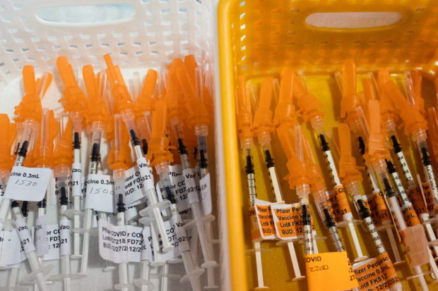 FILE PHOTO: Syringes filled with the Pfizer BioTech coronavirus disease (COVID-19) vaccine are seen at Sparrow Laboratories Drive-Thru Services in Lansing, Michigan, U.S., December 27, 2021. REUTERS/Emily Elconin