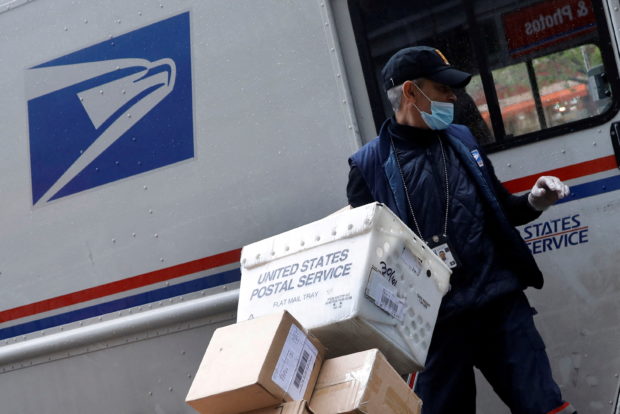 FILE PHOTO: A United States Postal Service (USPS) worker unloads packages from his truck in Manhattan during the outbreak of the coronavirus disease (COVID-19) in New York City, New York, U.S., April 13, 2020. REUTERS/Mike Segar/File Photo
