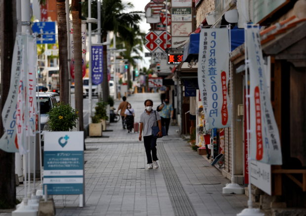 FILE PHOTO: People wearing protective face masks, amid the coronavirus disease (COVID-19) pandemic, walk along the Kokusai-dori in the prefectural capital Naha, on the southern island of Okinawa, Okinawa prefecture, Japan, October 25, 2021. Picture taken October 25, 2021. REUTERS/Issei Kato