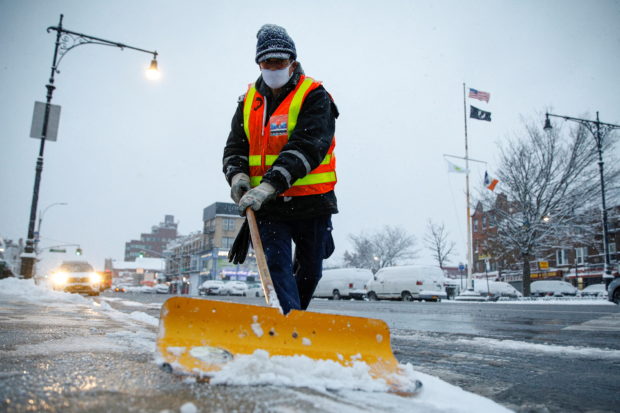 A New York City Transit worker clears snow from a sidewalk for the morning commute outside a subway station during a snow storm in Brooklyn, New York City, New York, U.S., January 7, 2022. REUTERS/Brendan McDermid