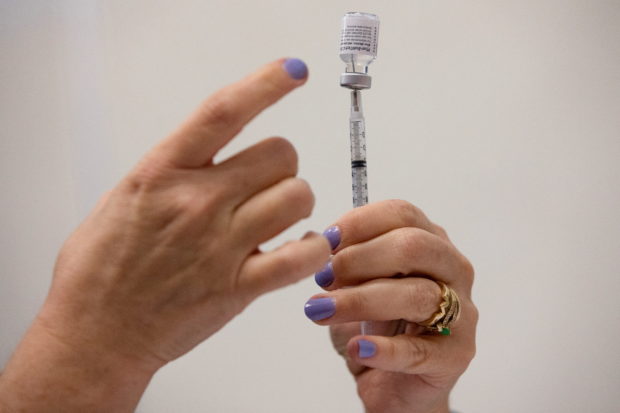 FILE PHOTO: A nurses fills up syringes for patients as they receive their coronavirus disease (COVID-19) booster vaccination during a Pfizer-BioNTech vaccination clinic in Southfield, Michigan, U.S., September 29, 2021. REUTERS/Emily Elconin