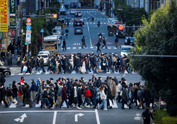Passersby wearing protective face masks walk on the street, amid the coronavirus disease (COVID-19) pandemic, in Tokyo, Japan January 15, 2022. REUTERS/Issei Kato