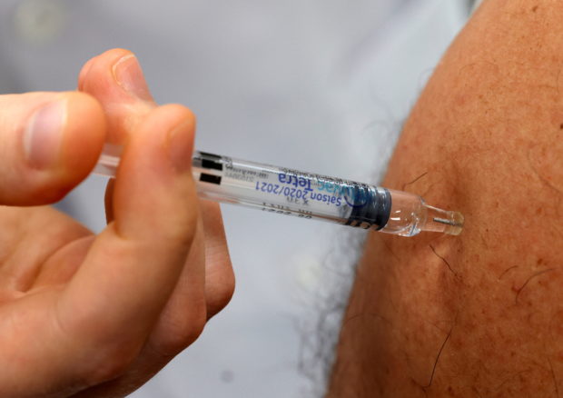FILE PHOTO: A doctor vaccinates a patient as part of the start of the seasonal influenza vaccination campaign in Gouzeaucourt, France, October 13, 2020. REUTERS/Pascal Rossignol/File Photo