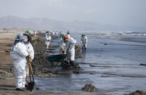 Workers clean up an oil spill caused by abnormal waves, triggered by a massive underwater volcanic eruption half a world away in Tonga, at the Peruvian beach in Ventanilla, Peru, January 18, 2022. REUTERS/Pilar Olivares