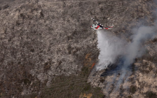 A Cal Fire water dropping helicopter drops its payload on a hot spot as the Colorado fire burns near Big Sur, California, U.S. January 22, 2022. REUTERS/Peter DaSilva/File Photo
